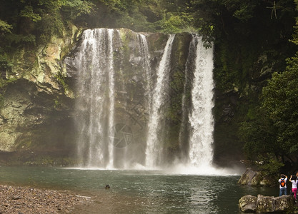 流动水济州岛的千吉燕瀑布是岛上最大的瀑布之一右下层的人提供一种规模感在最底层的人们提供了一种规模感河图片