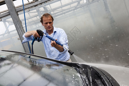 洗涤袖子男用高压水喷气式飞机用一个隔间洗其汽车挡风玻璃的人蜡图片