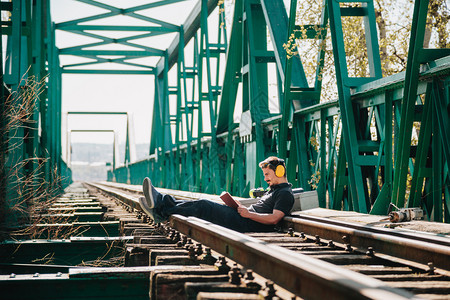 年轻的火车建筑工人坐在一旁看本关于旧钢铁路桥的书坐着严肃图片
