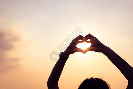 运动双手形成心脏状与日落光影轮廓图片
