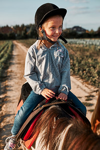 笑的小女孩学骑马56岁身戴头盔穿着玩得开心骑马时笑的小女孩在骑马一种课程农村图片