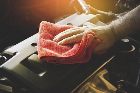 干净的肮脏工人手用红色微纤维布擦洗汽车发动机遮盖红色微纤维布图片