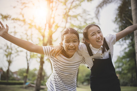 伙伴年龄在公共园里两个亚裔青少年快乐的情绪女孩图片