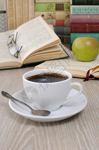 杯子乐趣阅读桌上一杯咖啡背景是一本带笔记的公开书图片