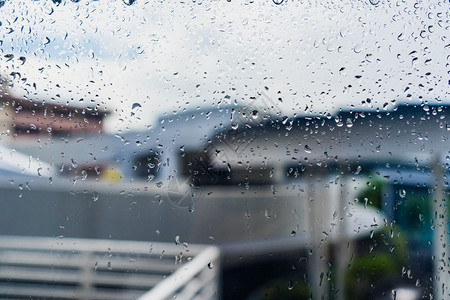 建造液体蓝色的窗玻璃上雨滴穿过被覆盖建筑物的窗口视图玻璃上落水窗户凝结图片