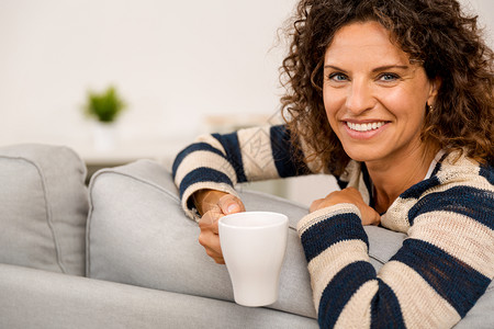 一种坐在沙发上喝咖啡的漂亮女人喝咖啡安详寒意图片