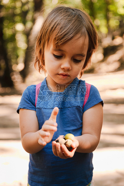 金发小女孩手上拿着橡子的小桃用背包在森林的路上冒险外部青年图片