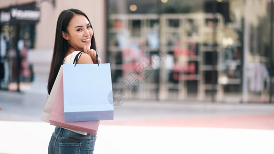 开支快乐的美丽亚洲妇女在购物中享受袋和商店式业概念幸福的拥有购物袋亚洲妇女士户外图片