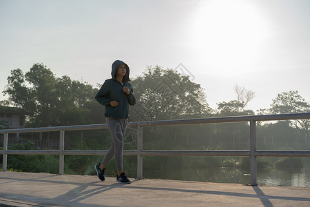 早晨年轻的亚洲人裔女在早园中慢跑图片