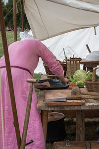 女士粉红图尼克人准备黑锅在帐篷里煮饭刀蔬菜图片