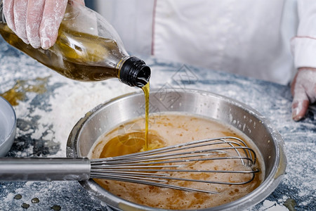 专业搅拌机调味品面包师在一家厨房的里把油放进钢碗里图片