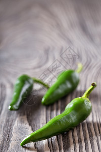 木制桌上三个绿色辣椒健康食物的概念三绿色辣椒在木制桌子上一个绿色辣椒自然明亮的图片