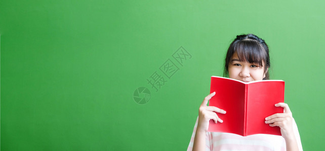 快乐的女覆盖站在绿色墙背景面前持有红色封书的亚洲女孩并拥有文本教育背景横幅和复制空间的文字教育背景图片