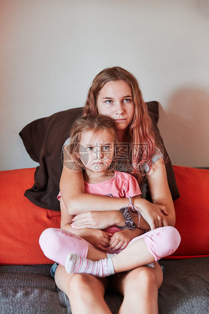 青少年女和她的妹一起看电视坐在沙发上专注的家里真实人情况Y我内部的年轻图片