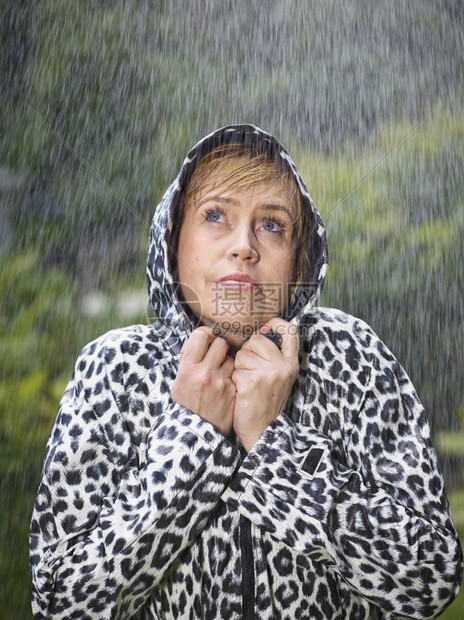 身穿雨衣季夏日背景绿色自然的成熟女士水庇护所图片