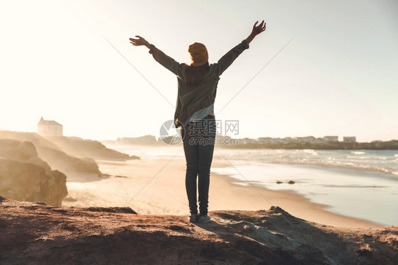 妇女举起双臂享受风景海悬崖女士图片