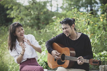 更年轻声学笑青的亚洲男女玩吉他和快乐感弹图片
