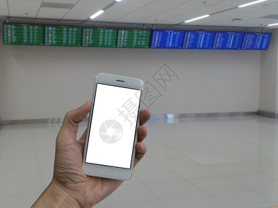 手持智能电话空白屏幕和机场候站背景模糊飞行日程的男子手持智能电话空白屏幕和运输飞机场乘客图片