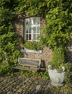 乡村的长椅旧农场墙上有绿色植物花园中老岩石上有座椅图片