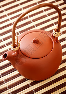 用具黄色的茶壶条纹竹餐巾上的棕色粘土水壶图片