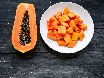 新鲜有机的切片熟木瓜水果的顶部视图半成木瓜果和黑本底白板上的碎块健康图片