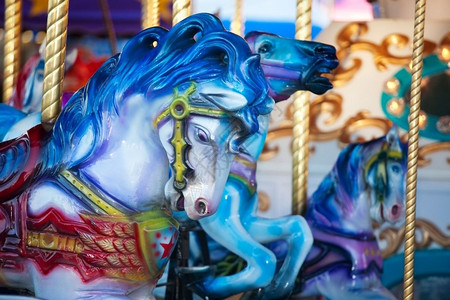 大约快乐的公园蓝木马骑在狂欢节的旋转木马上图片