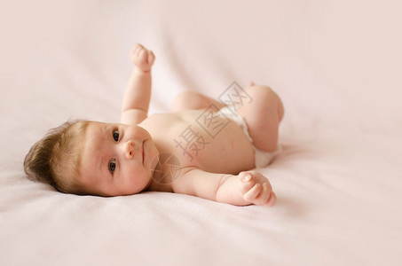 可爱的两个月大女婴躺在粉红色毯子背上说谎快乐的脸图片