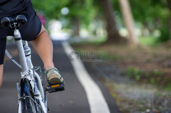 女士城市在后面亚洲女骑自行车者背后路边的女骑自行车者图片