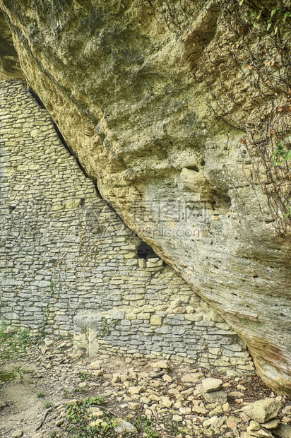 裂缝法国普罗旺斯Luberon地区森林之一的悬崖下方有块下面是一座旧石屋或稳定地的传统石墙被掩埋于法国普罗旺斯Luberon地区图片