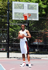 非裔美国人身穿白衣的非裔美籍男篮球运动员在一个暑假的篮球场上用双手举着球在户外放风站球场上着非洲人保持图片
