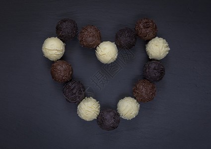 什锦的品种糖果黑石上巧克力松露的心形状图片