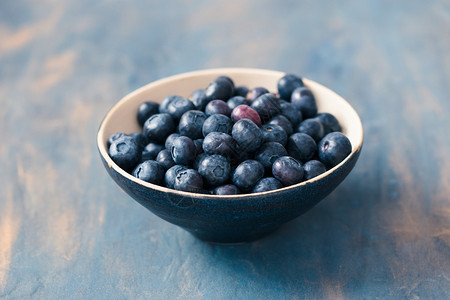 自然健康盛满一碗新鲜蓝莓的小放在桌上用蓝色涂漆营养图片