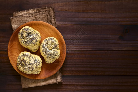 包子最佳烘烤木板上的自制种子面包卷用自然光照在黑木头的上面图片