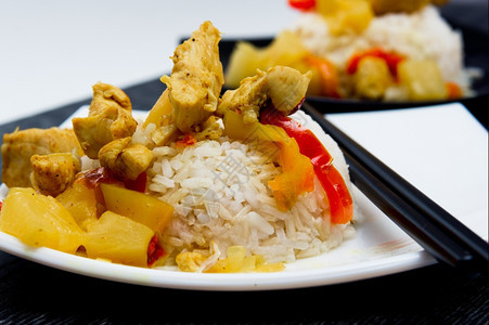 准备好的产品鸡肉配菠萝以白盘和黑上的米饭亚洲人图片