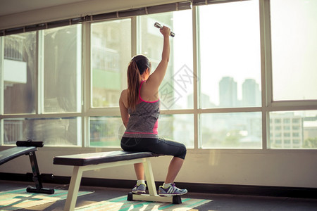 健身房拿着哑铃锻炼的女性背影图片