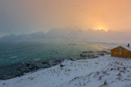 早晨太阳冬季挪威洛福登海湾山上黎明的雪瀑落天黑在黎明时冬湾下雪美丽的图片