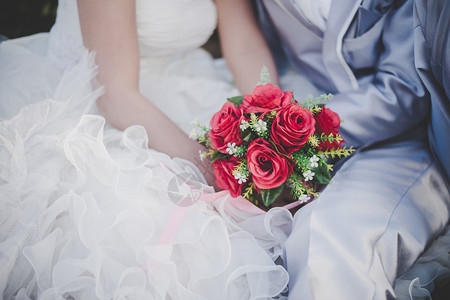 新娘手里握着婚礼红玫瑰花束新郎拥抱娘手中握着婚礼红玫瑰花束新郎拥抱娘在一起的结婚情人概念婚情爱女士美丽颜色图片