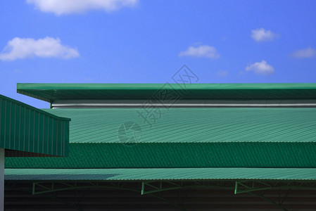 现代工厂大楼顶上蓝色天空背景的绿铁条弯曲金属屋顶外部的阳光贮存图片