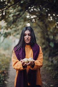 户外年轻女士在森林的摄像机上展示梨子橙手图片
