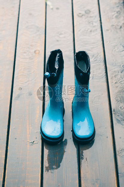 靴子常设外套在下雨时站木门廊上的蓝色水井图片