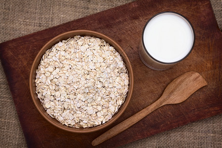 一碗的圆燕麦边上有一杯牛奶与自然光相照选择焦点聚于燕麦顶部饮食水平的满图片