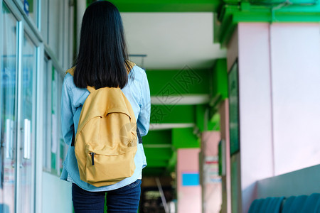 背着书包的女学生走在校园走廊里图片