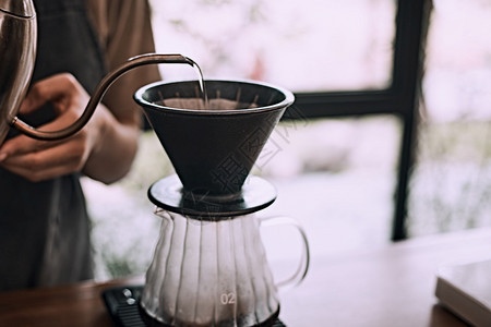 纸手滴咖啡用过滤器在咖啡地面上倒水的Barista手滴咖啡灌水的Barista热的早餐图片