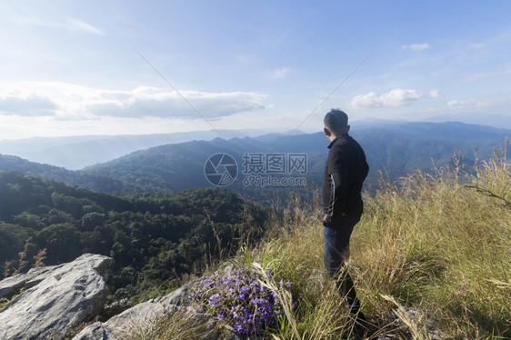 成功远足一个人站在悬崖上看着白天的山谷和峰旅行观冒险图片