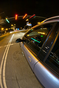 线条琥珀色镜子一辆汽车在夜间为交通灯的红而行驶图片