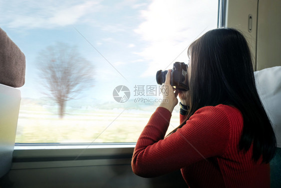旅行概念年轻女青在火车上坐着时带照相机拍铁路女孩片图片