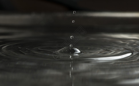 水滴下宏观拍到的深色底寒冷雨滴运动图片
