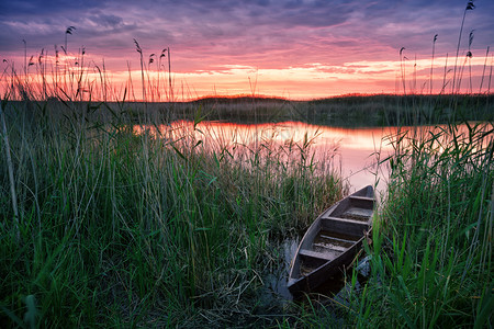 日落时在湖边的木船夕阳时在湖边的休养和自由概念月光之景黄昏时在湖边的木船奇幻天空下的单身银行水图片