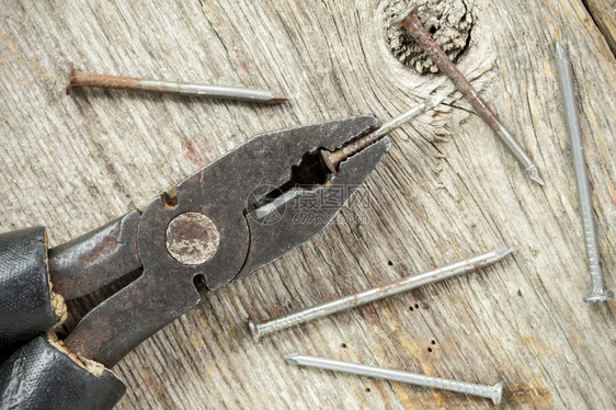旧用的在木制表背景上钉子的钳修理木头制品图片