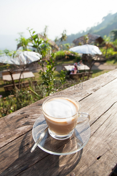 放松采取清晨的咖啡放在木制阳台上光照耀花园图片